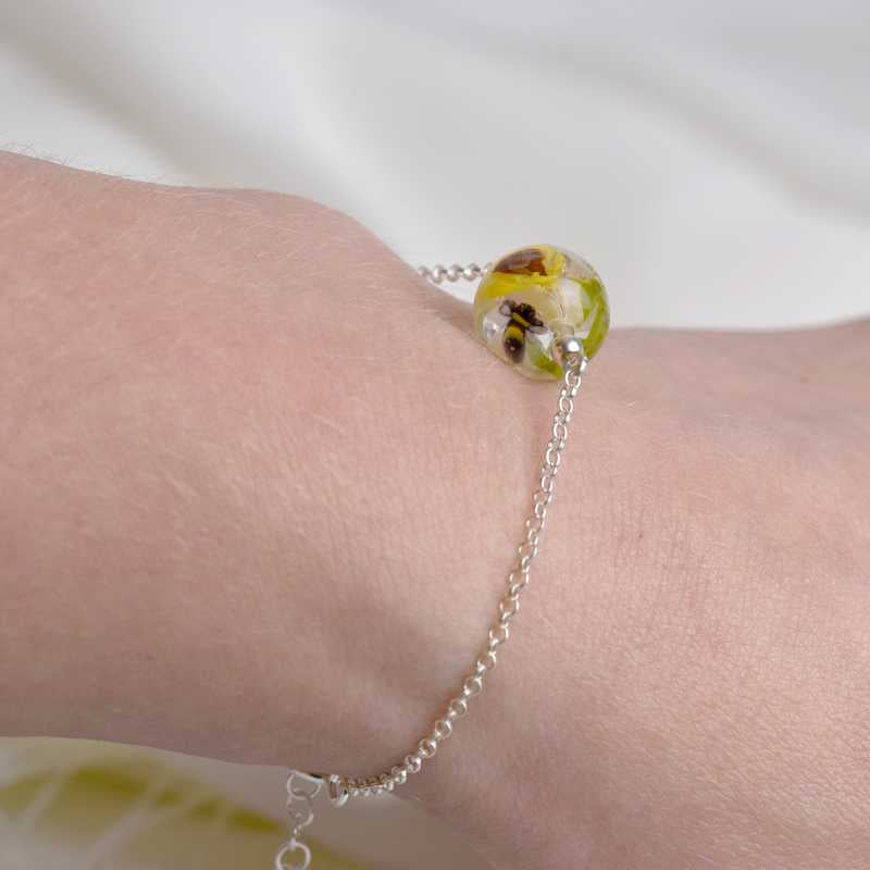 Bracelet en perles de verre artisanal porté sur poignée de femme