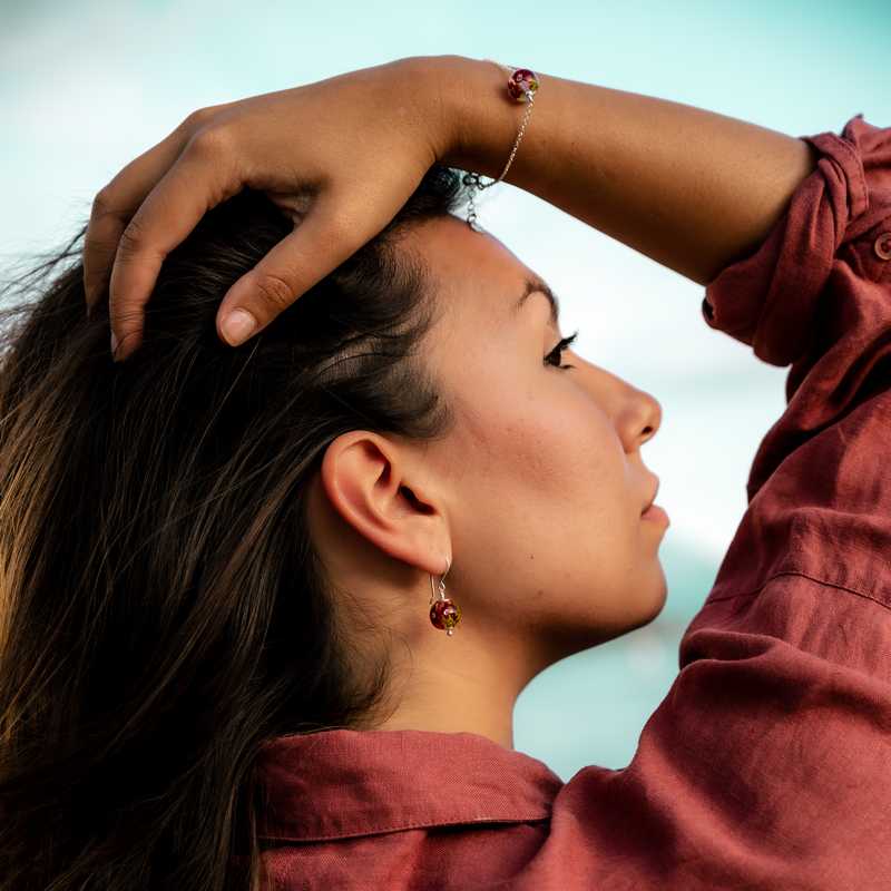 Boucle d'oreille en perles de verre artisanale sur oreille de femme